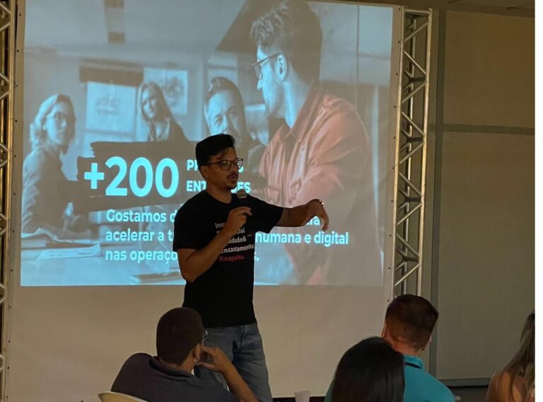 Rogério apresentando resultados em evento, tela ao fundo mostrando mais de 200 projetos entregues